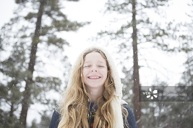 年轻女孩站在飘落的雪中的肖像图片素材
