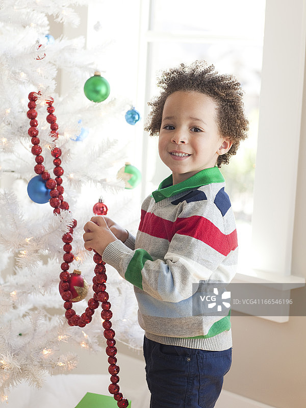 快乐的小男孩装饰圣诞树图片素材