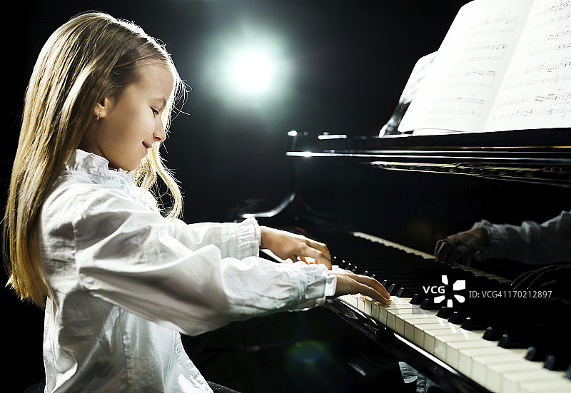 小女孩用乐谱弹钢琴图片素材