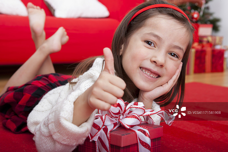 快乐的女孩拿着圣诞礼物竖起大拇指图片素材