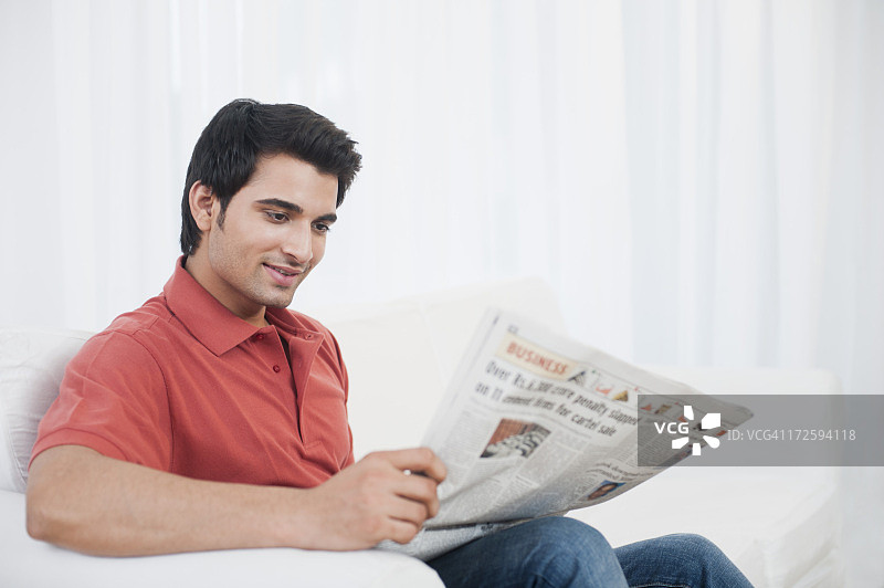 一个男人坐在沙发上看报纸图片素材