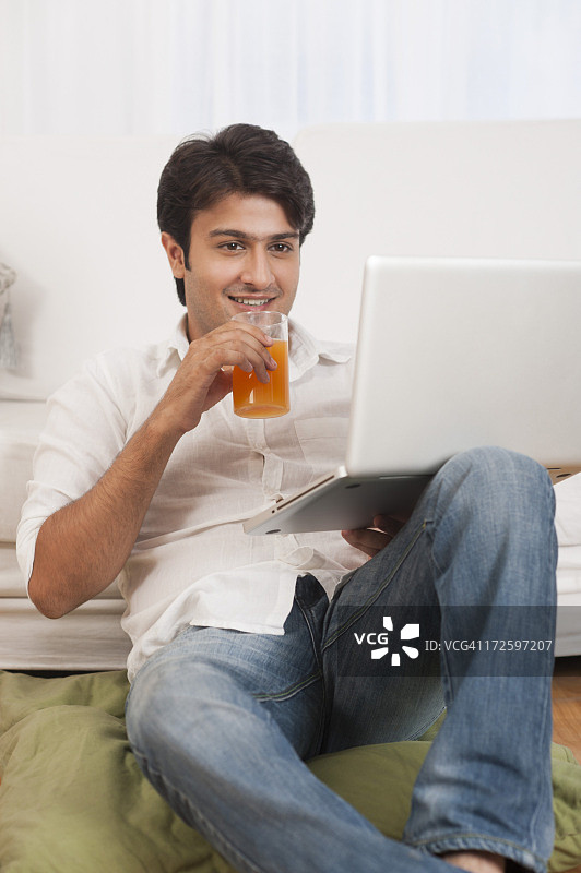 一个用笔记本电脑和一杯果汁的男人图片素材