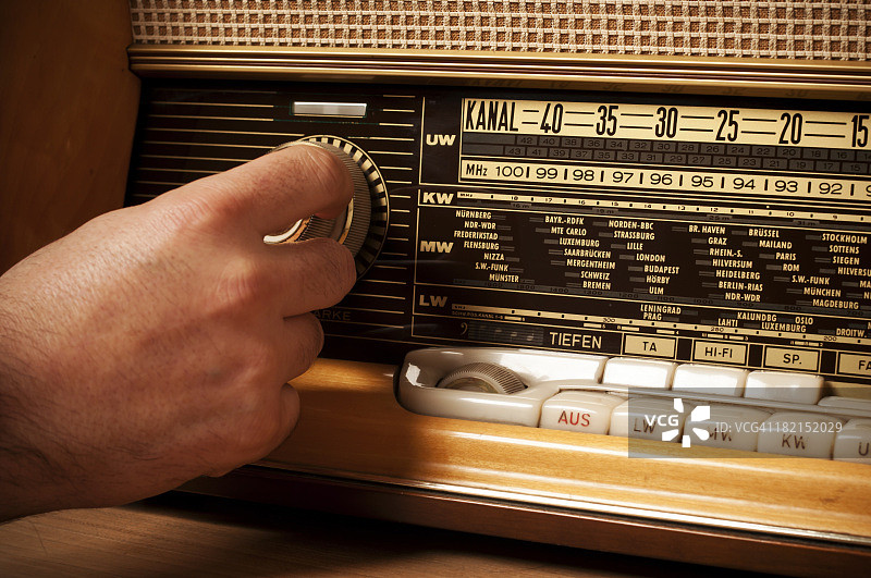 复古短波收音机与人的手在调谐器上图片素材