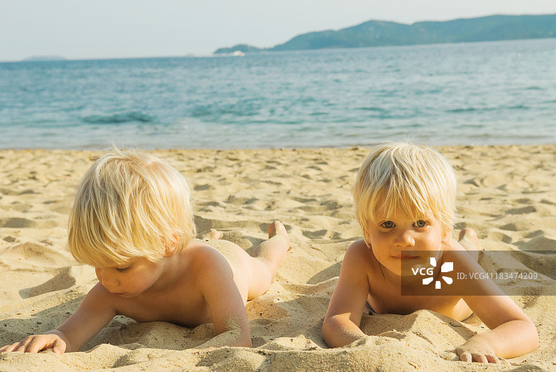 年轻的金发双胞胎躺在沙滩上图片素材