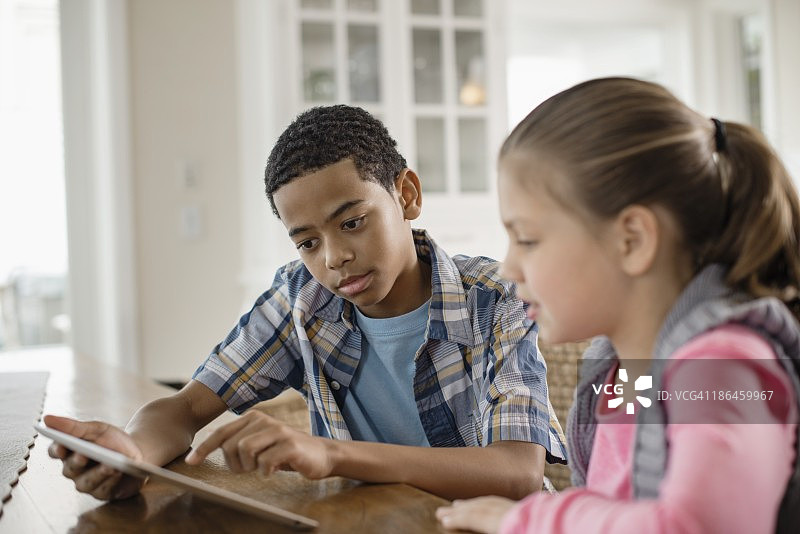男孩(8-9)和女孩(6-7)的肖像使用数字平板电脑图片素材