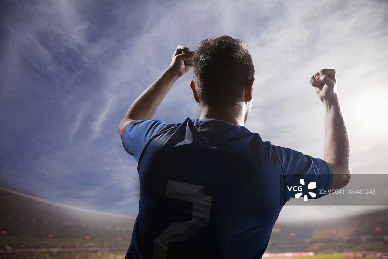 足球运动员高举双臂欢呼，体育场有天有云图片素材