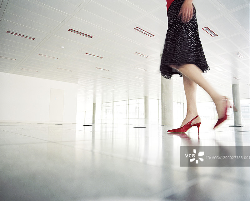 女人走过空荡荡的办公室，低截面(模糊动作)图片素材