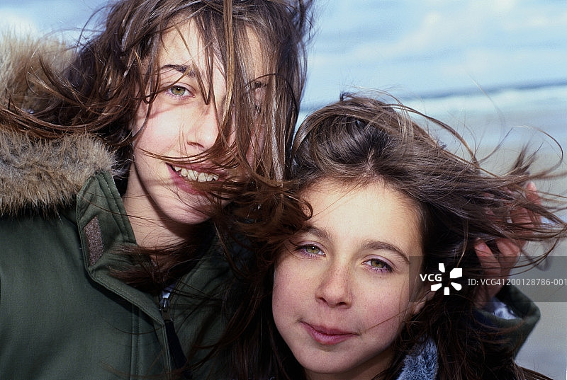 两个女孩(11-13岁)被风吹过的头发，肖像，特写图片素材
