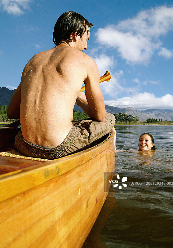 年轻男子在独木舟，后视镜，微笑的女人在湖图片素材