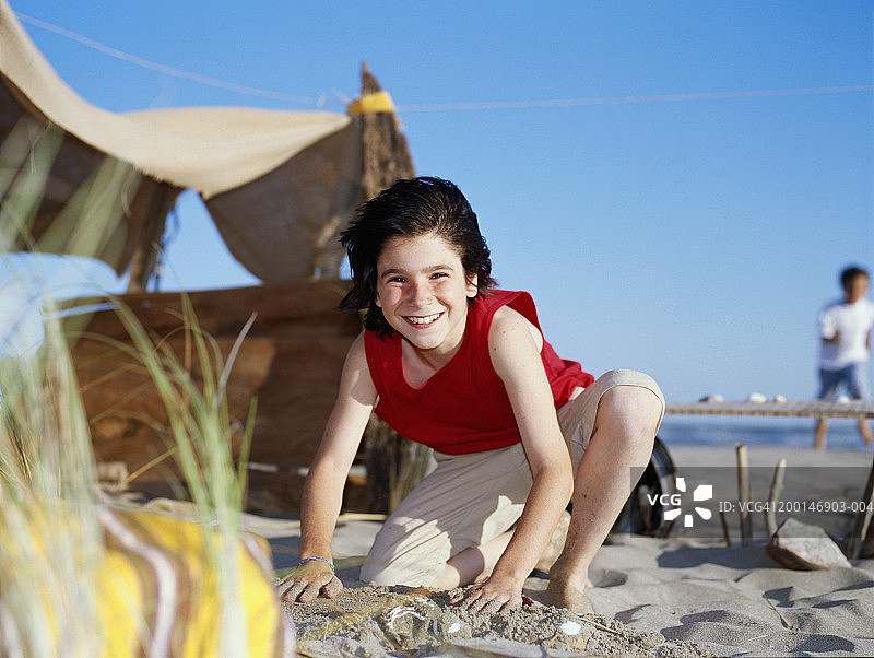 男孩(9-11)在海滩上的临时避难所外面玩耍，肖像图片素材
