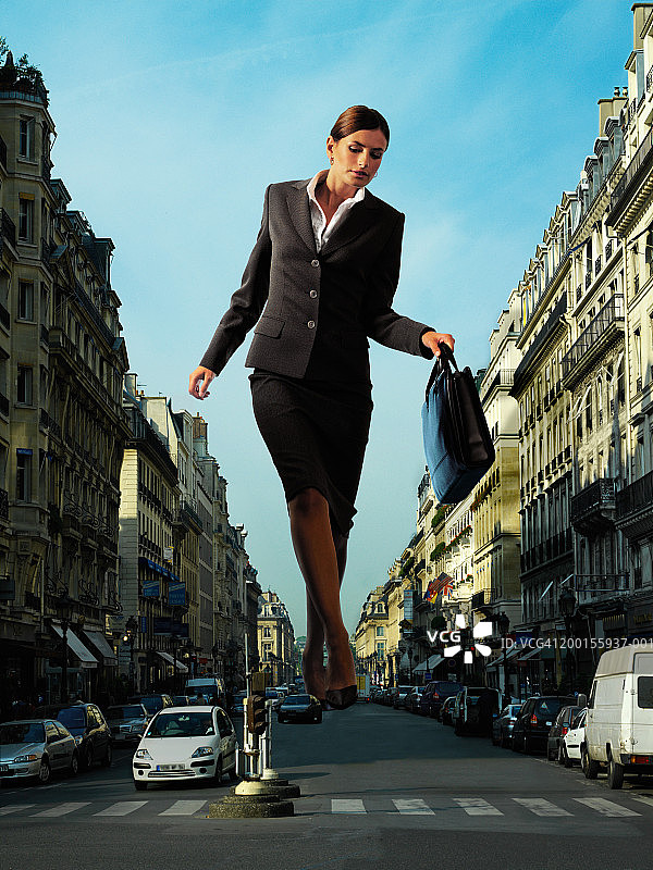 巨型女商人走在城市道路中间(数字合成)图片素材