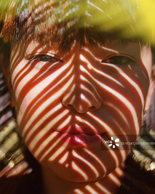 女人与棕榈叶的影子投在脸上，肖像，特写图片素材