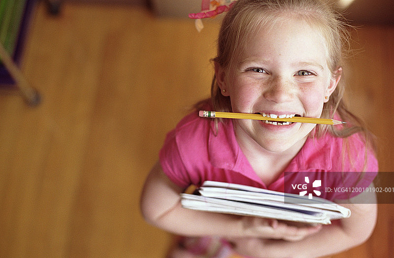 女孩(5-7)拿着书，咬着铅笔，肖像，高视眼图片素材