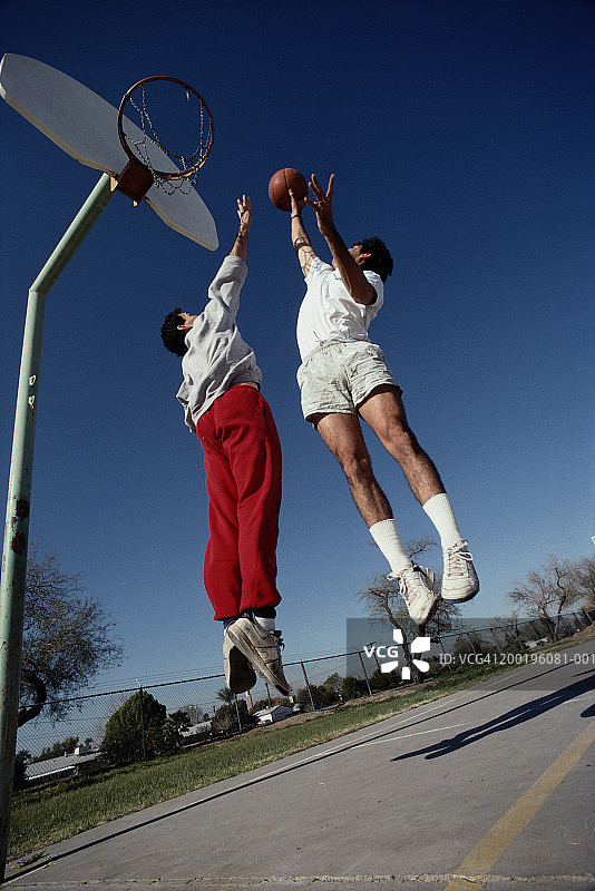 两个人打一对一的篮球，在户外，低角度观看图片素材