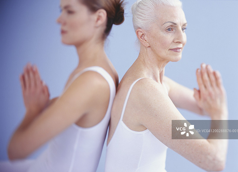 两个女人穿着白色紧身衣背靠背在瑜伽姿势图片素材