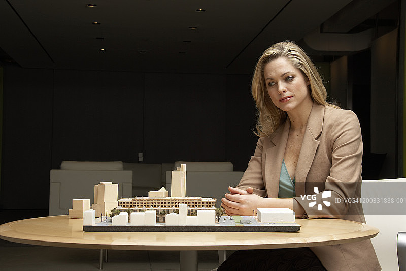 年轻女子看着桌子上的建筑模型图片素材