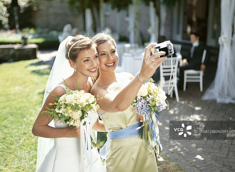 新娘和伴娘微笑着给自己拍照图片素材