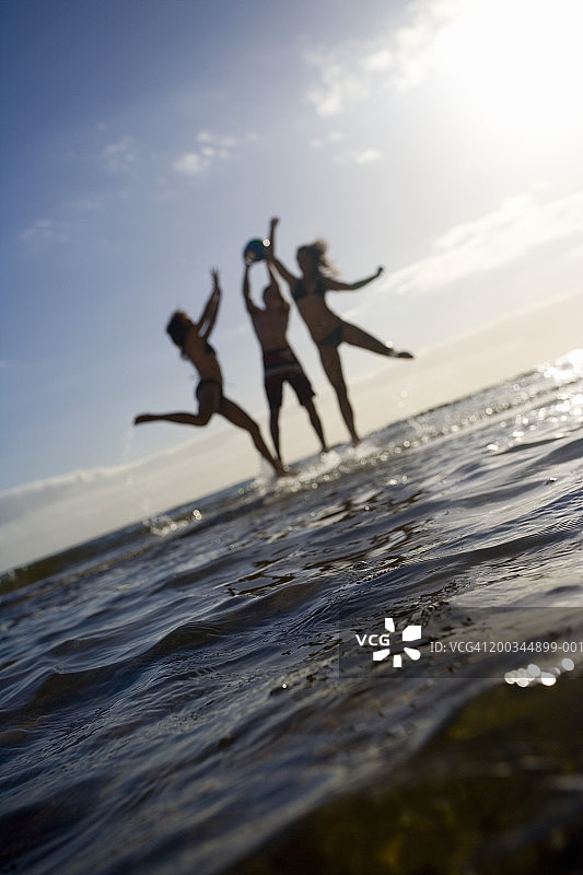 两个十几岁的女孩和男孩(13-16岁)跳进海里接球图片素材