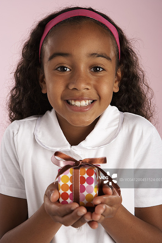 女孩(8-10)拿着礼物，微笑着，画像图片素材