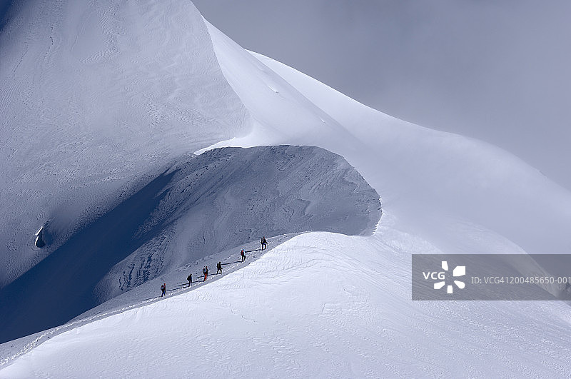 登山者穿越雪脊，高视阔步图片素材