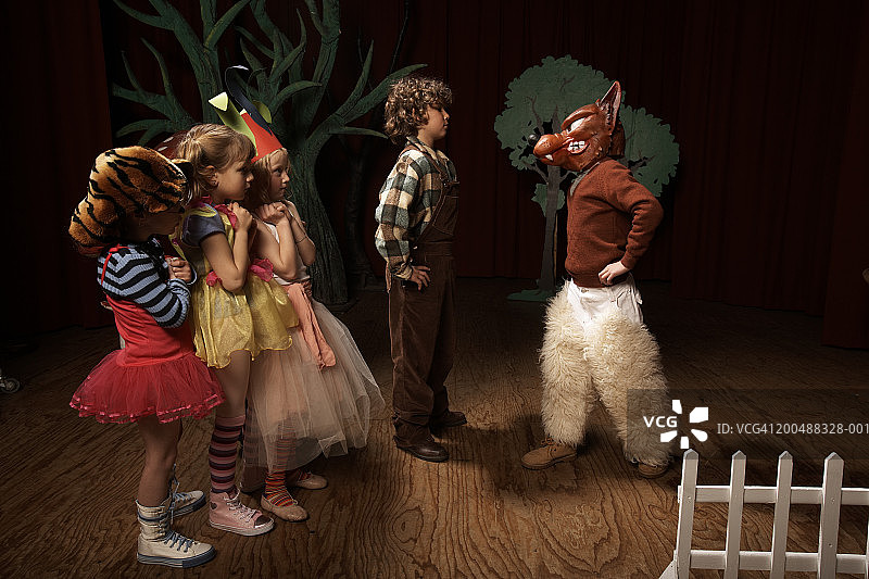 儿童(5-12岁)在舞台上表演，一个男孩面对坏狼图片素材