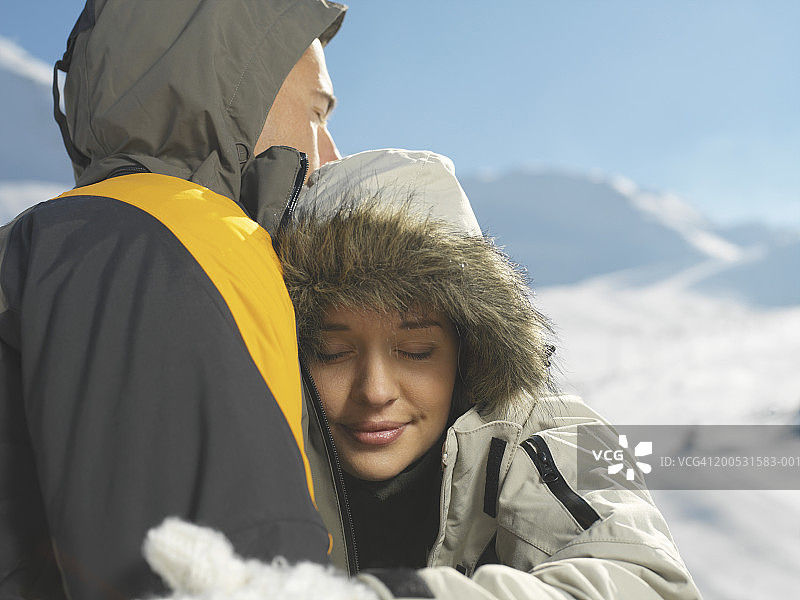 一对情侣在白雪覆盖的斜坡上拥抱，特写图片素材