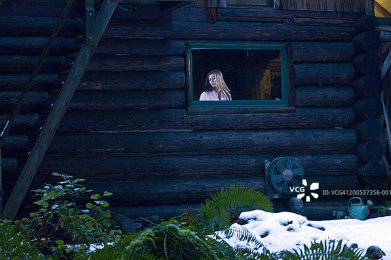 少女(14-16岁)站在小木屋的窗口，冬天图片素材