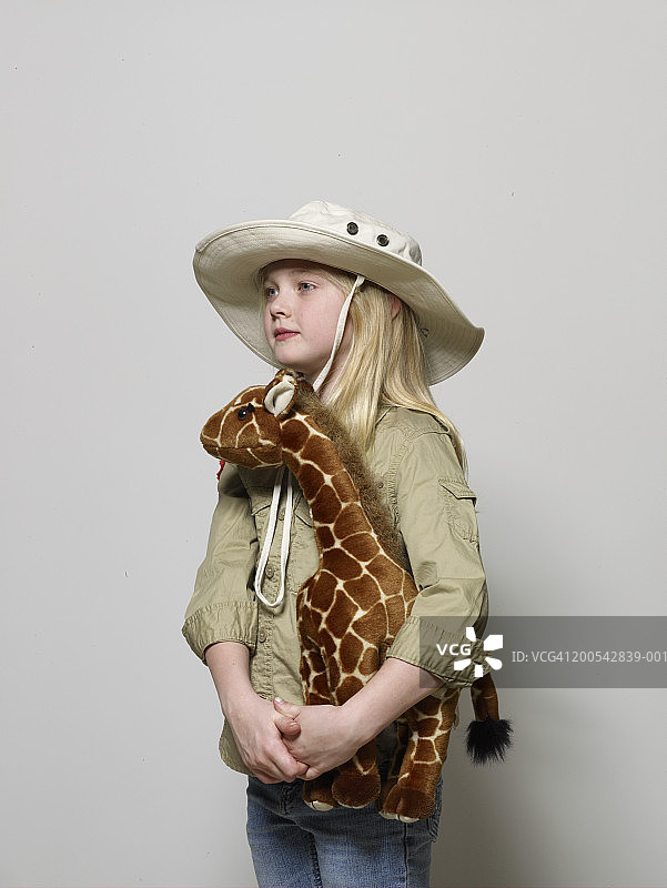 女孩(6-8岁)装扮成动物园管理员，抱着长颈鹿图片素材