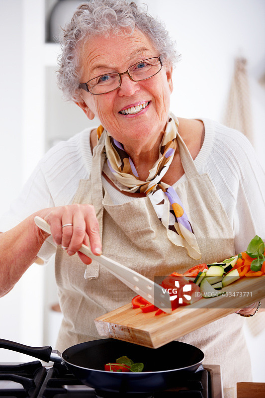 一个老女人微笑和烹饪食物的特写图片素材