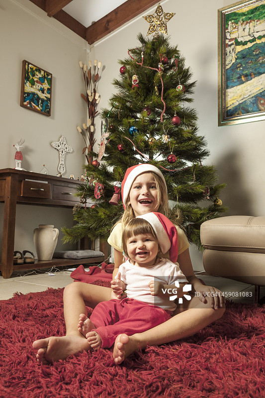 小女孩和妹妹在圣诞树前图片素材