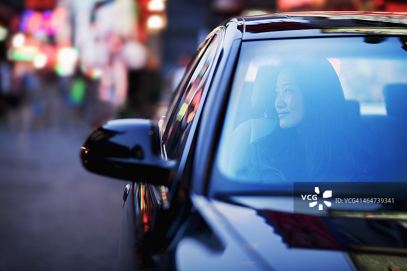 宁静的女人透过车窗看城市的夜生活图片素材