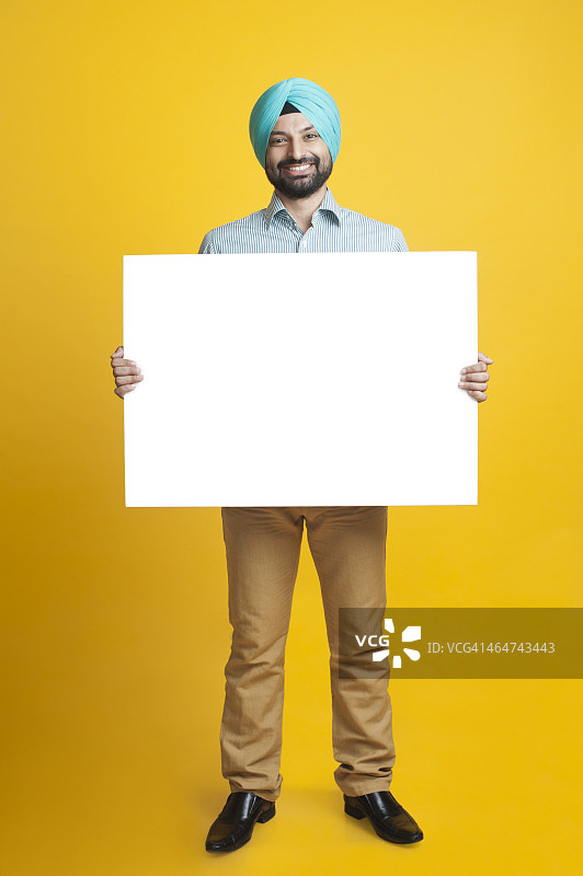 一名锡克教男子微笑着举着空白标语牌的肖像图片素材