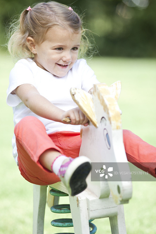 小女孩骑着木马，肖像图片素材