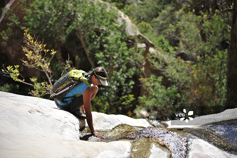 女性徒步者蹲在岩石上，威尔逊山，红石峡谷，内华达州，美国图片素材