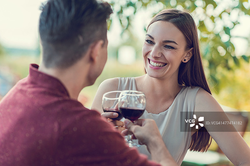 幸福的年轻夫妇用葡萄酒敬酒。图片素材