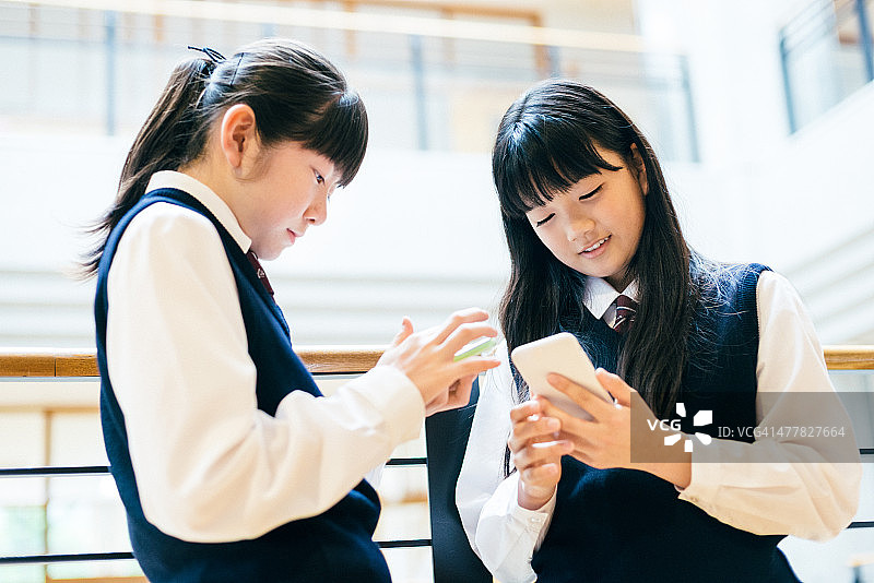 日本高中女生在学校使用智能手机图片素材