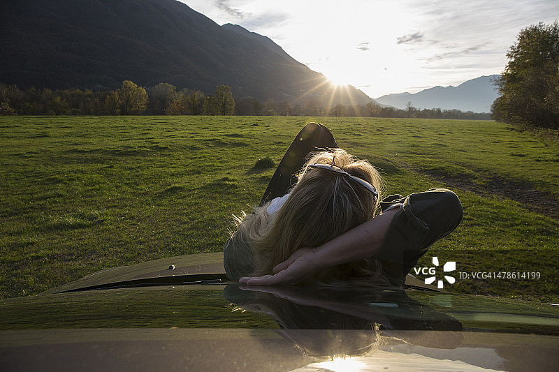 女人放松在汽车引擎盖上图片素材