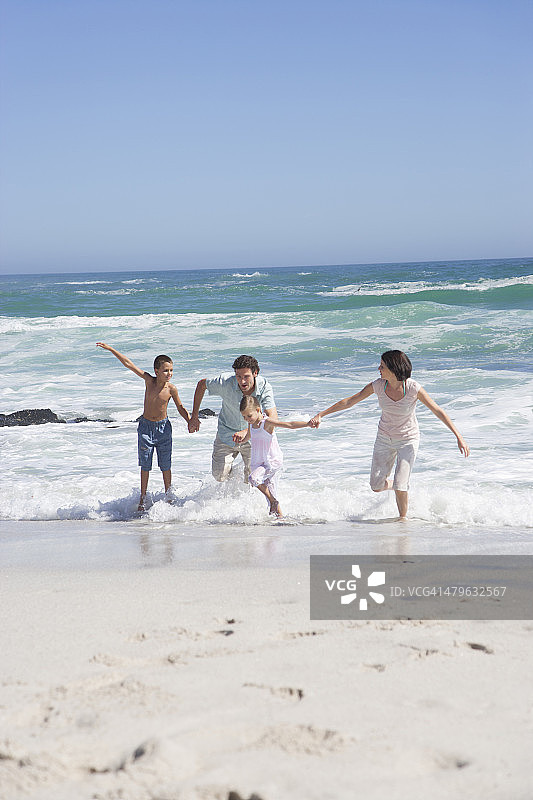 一家人手牵着手在海滩上图片素材