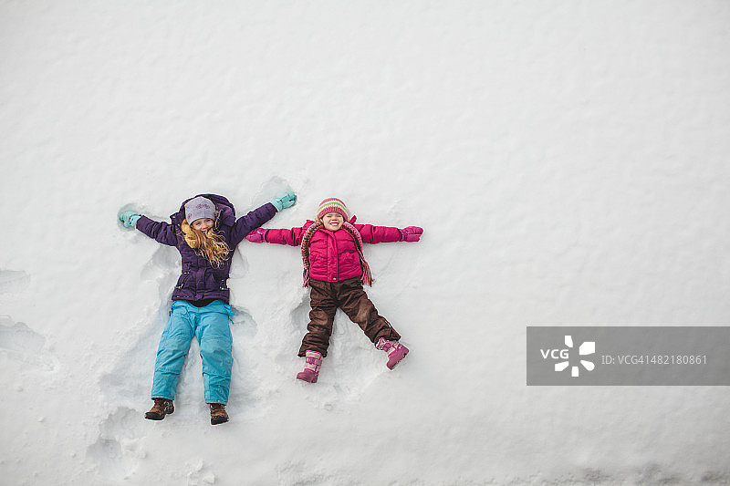 两姐妹在玩，在雪地里做雪天使图片素材