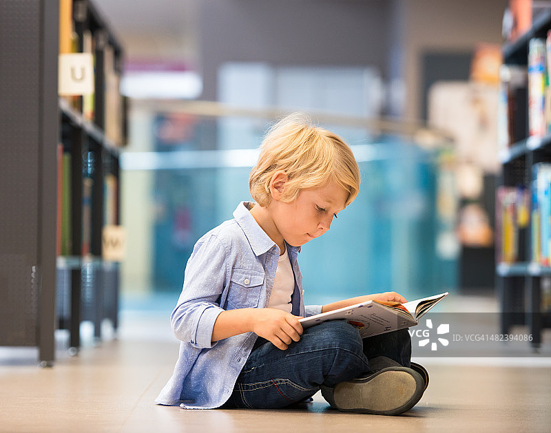 可爱的小男孩坐在图书馆里图片素材