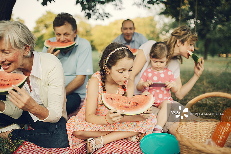 几代同堂的一家人在野餐时吃西瓜。图片素材