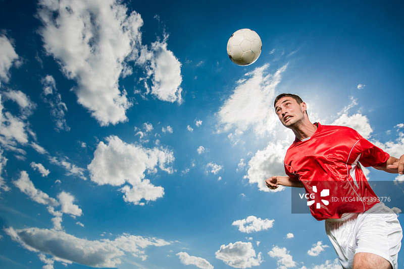 足球运动员把球顶向天空。图片素材