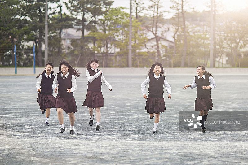 日本学生女生在学校操场上跑步图片素材
