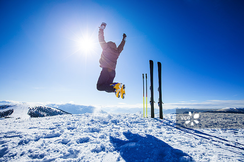 快乐的高山滑雪者在顶部的空中跳跃图片素材
