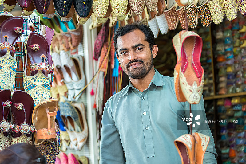 在阿联酋迪拜的露天市场，一名小贩正在销售中东鞋图片素材
