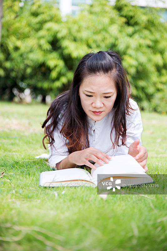 一个亚洲女人在公园里看书图片素材