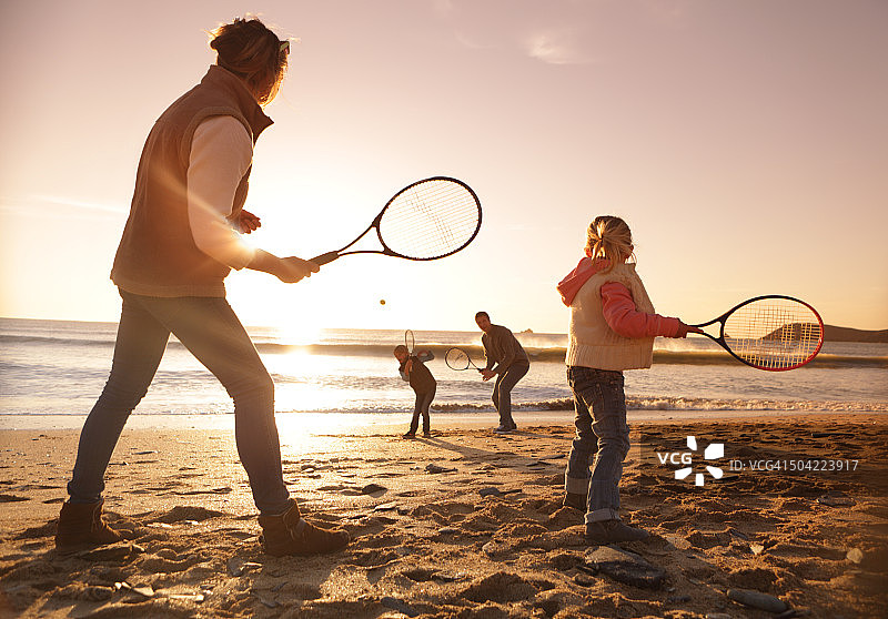 日落时分一家人在沙滩上打网球图片素材