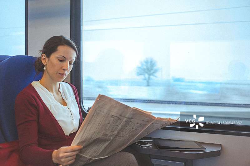 年轻的商业女性在上班路上看报纸图片素材