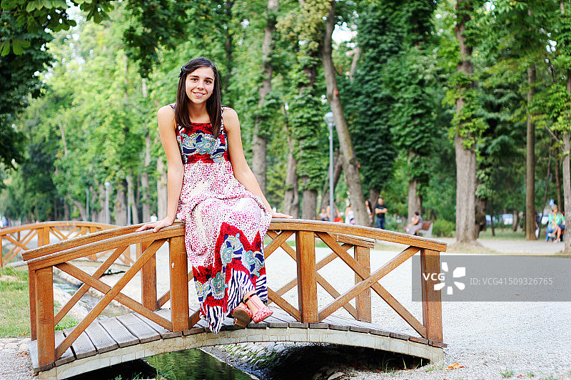 女孩坐在公园里的一座小木桥上图片素材