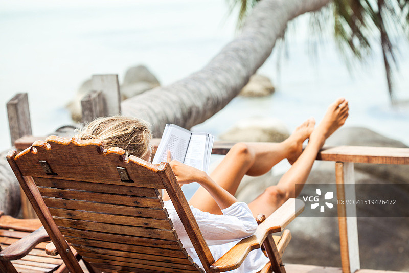 一个年轻女子在热带岛屿上放松的时候读一本书图片素材